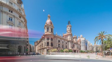 Panorama, Plaza de Ayuntamiento 'da Valencia Belediye Binası' nı (Ajuntament de Valencia) gösteriyor. Mavi gökyüzünün altında saat kulesi olan tarihi bir bina. İspanya 'nın ana meydanında gezinen insanlar