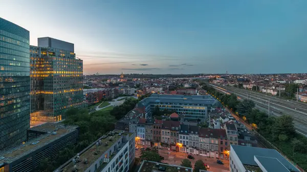 Brüksel kentsel manzarasının yerleşim alanlarıyla ofis gökdelenlerini harmanlayan hava gününden geceye geçiş zamanı. Yeşil park çimenleri, tarihi çatılar ve Belçika 'nın modern mimarisi.