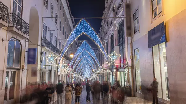 Lizbon şehir merkezindeki Chiado Carmo sokağındaki Noel ışıkları ve dekorasyonları gece aşırı hızlandı. İnsanlar aydınlanmış kemerlerin altında yürürler. Portekiz 'de festival dekorlu tatil atmosferi
