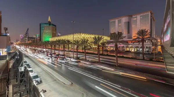 Suudi Arabistan, Riyad 'daki Kral Fahd Yolu' nun hava-gece zaman çizelgesi. Modern kuleler ve gökdelenlerle çevrili aydınlık Ulusal Kütüphane 'nin yakınındaki arabalarla ve taksilerle hareketli bir trafik manzarası.