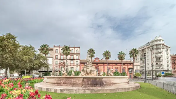 Şehrin en güzel çeşmelerinden biri olan Sevilla 'daki Hispalis Çeşmesi renkli çiçekler ve tarihi binalarla çevrili. Arka planda bulutlu bir gökyüzü ile hızlandırılmış zaman çizelgesi.