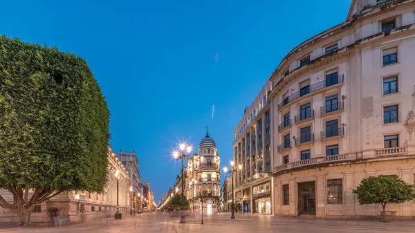 Avenida de la Constitucion, Seville, İspanya 'da günden geceye zaman dilimi. Modern sokak lambaları, yayalar ve kentsel atmosferi olan tarihi mimari. Iconic Adriatica binası gün batımından sonra parlıyor.