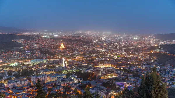 Alacakaranlıkta Tiflis şehri, Gürcistan 'dan gece geçiş zamanı. Şehir merkezinin ve Tiflis 'teki Kura Nehri' nin üst manzarası. Gün batımından sonra Gürcistan başkentinin havadan görünüşü