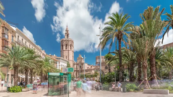 Valencia, İspanya 'da Plaza de la Reina' nın panoramik zaman atlaması. Tarihi bir kilise kulesi, hareketli kafeler ve sıcak Akdeniz semaları altında palmiyeleri olan merkezi bir çeşme..