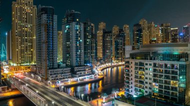 Dubai Marina 'nın gece görüş açısının en üstünde. Suda hafif tekne izleri ve yolda arabalar var. Dubai, BAE. Çatıdan hava görüntüsü