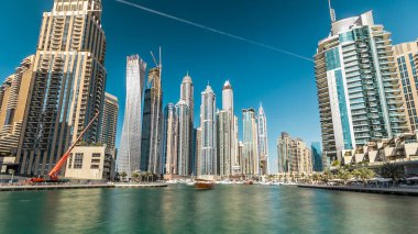 Dubai Marina modern yüksek kuleleri, Birleşik Arap Emirlikleri 'ndeki gezinti zamanı aşırı hızından dolayı suya yansıdı. Dubai 'de bir bölge ve yapay bir kanal. Mavi bulutlu gökyüzü
