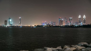 Dubai İnternet Bölgesi 'nin aydınlık kuleleri, geceleri palmiye adasından gelen su saatlerine yansıyor.
