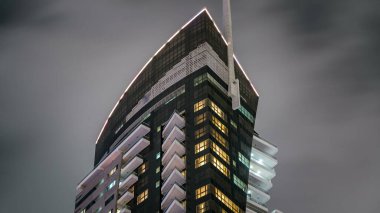 Geceleri iş yerlerindeki modern binaların zaman çizelgelerine bak. Parlak pencereli cam cepheli gökdelenler. Ekonomi ve finans kavramı. Dubai, BAE