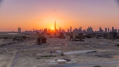 Akşam saatlerinde Dubai şehir merkezinin ufuk çizgisi ile gün batımı. Çölde inşa edilmiş modern gökdelenlerin güzel gökdelenleri. Havaalanı yakınındaki binadan hava görüntüsü