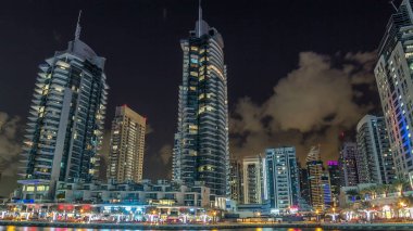 Dubai Marina gezinti güvertesinde yatlar ve modern kuleler ile Dubai 'deki deniz kıyısından yansıyan su, Birleşik Arap Emirlikleri. Dubai Marina, Dubai 'de bir şehirdir..