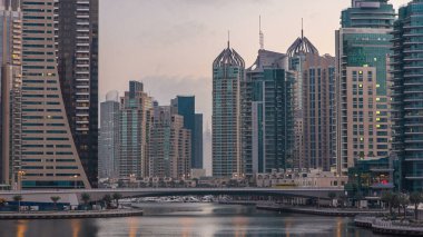Dubai Marina Kanalı, modern kuleleri ve yatları olan liman kenti Dubai 'deki köprüden gece gündüz geçiş zamanı olan Birleşik Arap Emirlikleri' ne yansıyor. Güneş doğmadan önce etraftaki gökdelenler