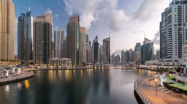 Dubai Marina Kanalı, modern kuleleri ve yatları olan liman kenti Dubai 'deki köprüden gece gündüz geçiş zamanı olan Birleşik Arap Emirlikleri' ne yansıyor. Güneş doğmadan önce etraftaki gökdelenler