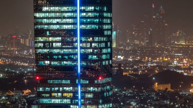 Büyük modern şehrin ofis kulesindeki pencerelerin hava görüntüsü. Arka planda trafik, aydınlık gökdelenler, ofis binaları ve Dubai marina kuleleri var. Ticaret Koyu, Birleşik Arap Emirlikleri