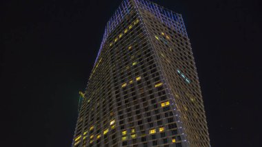 Dubai Marina 'daki gezinti alanının gece görüş alanı. Modern kuleler. Zaman ayarlı yanıp sönen ışıklar, Birleşik Arap Emirlikleri. Çarpık kule yukarı bak