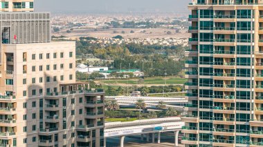 Golf sahası ve Dubai silueti gündüz vakti Şeyh zayed yolunda trafik varken. Golf sahasının yeşil çimenleri arka planda şehrin gökdelenleri gün batımında. Yan taraftaki modern kuleler