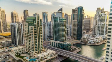 Gün batımından önce Dubai, BAE 'de yüzen yat ve teknelerle Dubai Marina gezinti ve kanalının hava görüntüsü. Modern kuleler ve köprüdeki trafik