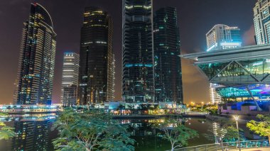 Rıhtımdaki ışıklandırılmış gökdelenlerin gece görüş açısını hızlandırın. Dubai, BAE 'deki Jumeirah Gölü Kuleleri' ndeki konut binaları. Balkondan hava görüntüsü