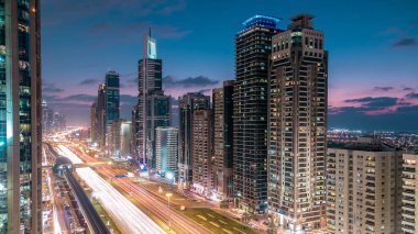 Dubai Kuleleri 'nin şehir merkezinden gece gündüz geçiş zamanı. Gün batımından sonra Şeyh Zayed 'in gökdelenli hava manzarası. Yollarda ve metro hattında trafik vardı. Güzel bulutlu gökyüzü