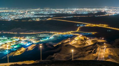 Jebel Hafeet 'te gece vakti kayalar ve kıvrımlı yollar. Öncelikli olarak Al Ain 'in çevresinde yer alan dağ aydınlanmış şehir üzerinde etkileyici bir manzara sunuyor. Yukarıdan hava görünümü