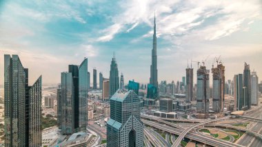 Gün batımında Dubai şehir merkezindeki gökdelenler ve Şeyh Zayed kavşağında yol trafiği olan gökyüzü çizgisi. Kule çatısından üst hava manzarası. Gökyüzündeki bulutlar. Dubai, Birleşik Arap Emirlikleri