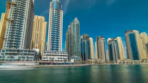 Dubai Marina Kuleleri, Birleşik Arap Emirlikleri 'ndeki gezinti güvertesi zaman aşımından suya yansıdı. Dubai Marina, Dubai 'de yer alan bir şehirdir. Mavi bulutlu gökyüzü