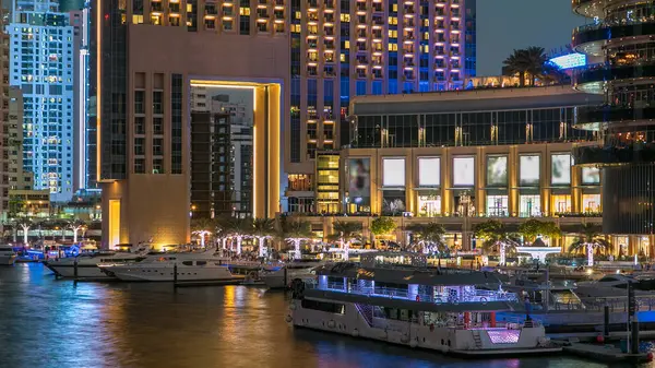 Dubai Marina rıhtımında yatları ve Dubai 'deki köprüden gece geçişine kadar alışveriş merkezi yakınlarında modern kuleleri olan Birleşik Arap Emirlikleri. Dubai Marina, Dubai 'de bir şehirdir.