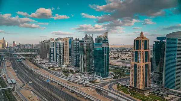 Dubai marina gökdelenlerinin ve Jumeirah göl kulelerinin hava panoramik manzarası Sheikh zayed yolundaki trafiği gösteriyor. Bulutlu mavi gökyüzü ile gün batımı zamanı