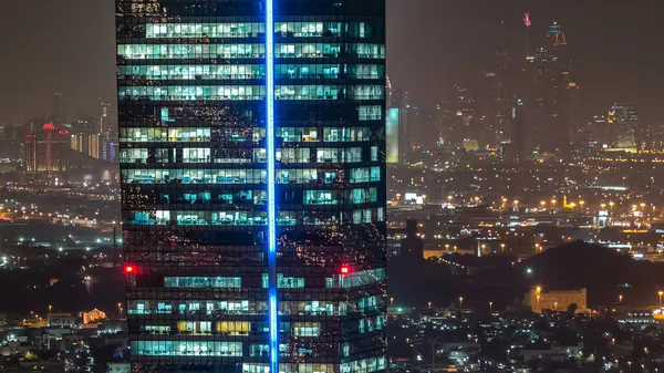 Büyük modern şehrin ofis kulesindeki pencerelerin hava görüntüsü. Arka planda trafik, aydınlık gökdelenler, ofis binaları ve Dubai marina kuleleri var. Ticaret Koyu, Birleşik Arap Emirlikleri