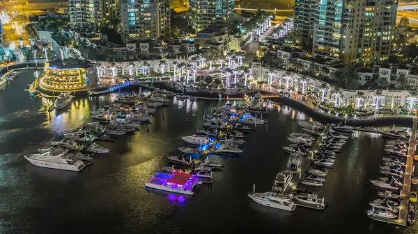 Dubai Marina gezinti güvertesi ve kanalı, Dubai, BAE 'de yüzen yat ve teknelerle dolu. Işıklı çeşme yanıp sönen ışıklar ve yol manzaralı trafik.