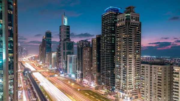 Dubai Kuleleri 'nin şehir merkezinden gece gündüz geçiş zamanı. Gün batımından sonra Şeyh Zayed 'in gökdelenli hava manzarası. Yollarda ve metro hattında trafik vardı. Güzel bulutlu gökyüzü