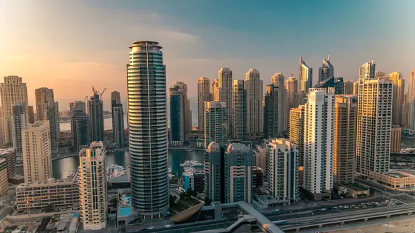 Dubai Marina ve Dubai, BAE 'deki JLT gökdelenlerinin günbatımı zaman çizelgesinde. Modern kuleler ve Şeyh zayed yolundaki trafik yukarıdan metro ve tramvay istasyonlarıyla
