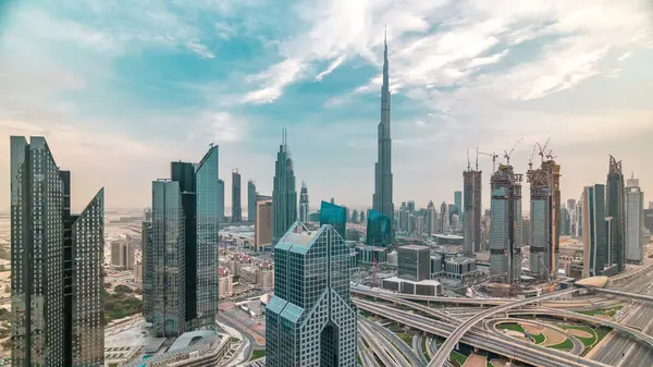 Gün batımında Dubai şehir merkezindeki gökdelenler ve Şeyh Zayed kavşağında yol trafiği olan gökyüzü çizgisi. Kule çatısından üst hava manzarası. Gökyüzündeki bulutlar. Dubai, Birleşik Arap Emirlikleri