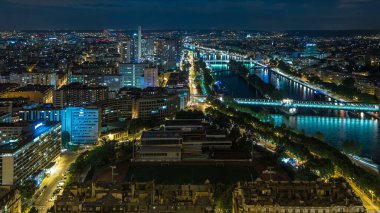 Paris Şehri ve Seine Nehri 'nin, Eyfel Kulesi gözlem güvertesinin tepesinde çekildiği Hava Gecesi zaman çizelgesi. Akşam aydınlatması. Rıhtım kenarındaki yollarda trafik vardı.
