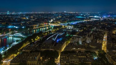 Paris City ve Seine nehrinin Eiffel Kulesi gözlem güvertesinin tepesinde köprülerle çekilmiş zaman çizelgesi. Akşam aydınlatması. Yollarda trafik