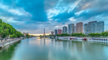 Eyfel Kulesi, Seine Nehri 'nde ve Fransa' nın Paris şehrinde teknelerle gün doğumu zamanı. Mirabeau Köprüsü 'nden gökyüzü dramatik bir şekilde görünüyor. Modern binalar ve yol trafiği. Özgürlük Anıtı