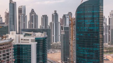 Dubai iş hangarı kuleleri gün batımında hava zaman tünelinde. Bazı gökdelenlerin çatı manzarası ve inşaat halindeki yeni kuleler.