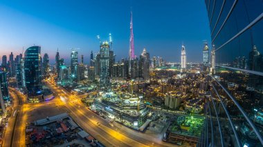 Dubai Şehir Merkezi 'nden geceye geçiş zamanı. Geceleri büyük, fütüristik şehir üzerinde hava manzarası. Dubai 'nin gökdelenleri camdan yansıyor, Birleşik Arap Emirlikleri. Akşam gökyüzü çatıdan yükseliyor