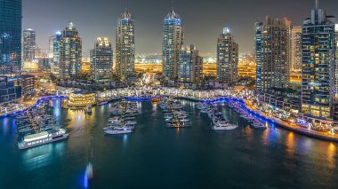 Dubai Yat Limanı gece timelapse, Glittering ışıklar ve açık bir akşam sırasında en yüksek gökdelenler. Işıklı kuleleri, yatlar ve arka plan üzerinde yolda trafik