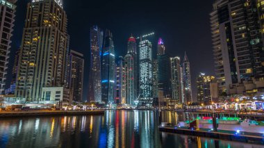 Dubai Yat Limanı defne yatların bir tekne timelapse hyperlapse. En yüksek gökdelenler gece ışıklı kanal suya yansıyan