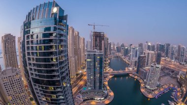 Dubai Marina gezinti güvertesi ve kanalı, gün batımından sonra Dubai, BAE 'de yüzen yat ve teknelerle panoramik hava manzaralı. Modern kuleler ve yoldaki trafik.