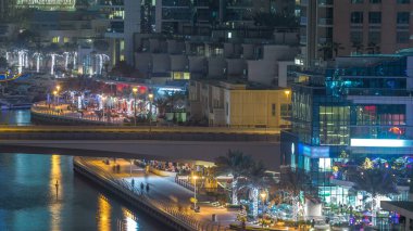 Su kanalı ve Dubai Marina manzarası, gece timelapse güvertede. Konut kuleleri aydınlatma ve aydınlatma ile. Yat ve tekne trafiği olan bir köprü gökdelenler yüzen
