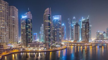Su kanalı ve Dubai Marina manzarası, gece timelapse güvertede. Konut kuleleri aydınlatma ve aydınlatma ile. Yat ve tekne trafiği olan gökdelenler yüzen