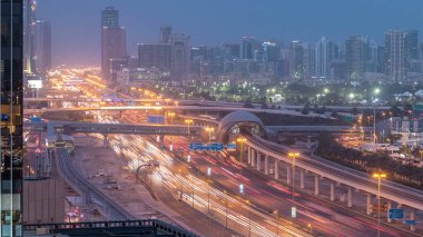 Jumeirah göl kulelerinin, gökdelenlerin ve Al Barsha bölgesinin gece gündüz geçiş zamanının havadan görüntüsü. Golf sahası ve metro hattı yakınlarındaki Şeyh Zized yolunda trafik var..