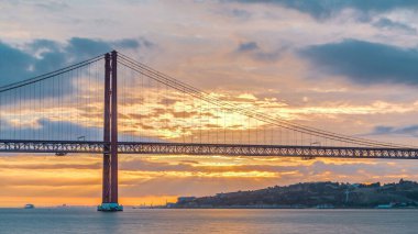 Lisbon city sunrise with April 25 bridge timelapse, River and waterfront early morning. Orange clouds on the sky