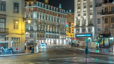 Dom Joao da Camara Square from Praca Dom Pedro IV or Rossio Square in Lisbon downtown night timelapse. Illuminated building and traffic on the road intersection