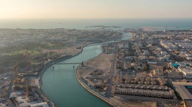 Downtown gökdelenler çatıdan gün batımı hava timelapse sırasında yaya köprüsü ile Dubai su kanalı. Yüzer tekneler ve vinçli şantiye