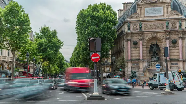 Saint-Michel Meydanı 'nın tarihi çeşmeli sokak manzarası, Paris. Arabalar ve insanlarla kavşakta trafik vardı. Yaz gününde bulutlu bir gökyüzü