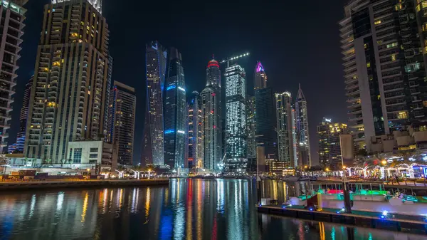 Dubai Yat Limanı defne yatların bir tekne timelapse hyperlapse. En yüksek gökdelenler gece ışıklı kanal suya yansıyan
