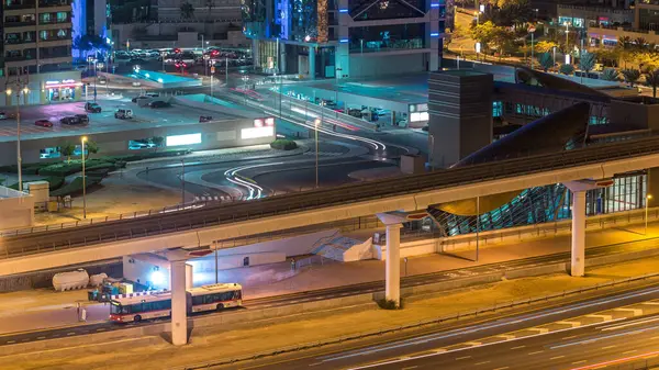 Jumeirah göl kuleleri gökdelenleri olan hava manzaralı bir gece şeyh zayed yolunda ve metro hattında araba parkı ve trafik var. Metro istasyonundan çıkışa yakın otobüs durağı. Dubai limanının çatısında.