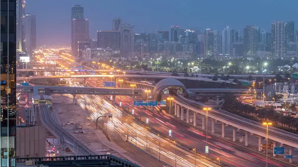 Jumeirah göl kulelerinin, gökdelenlerin ve Al Barsha bölgesinin gece gündüz geçiş zamanının havadan görüntüsü. Golf sahası ve metro hattı yakınlarındaki Şeyh Zized yolunda trafik var..
